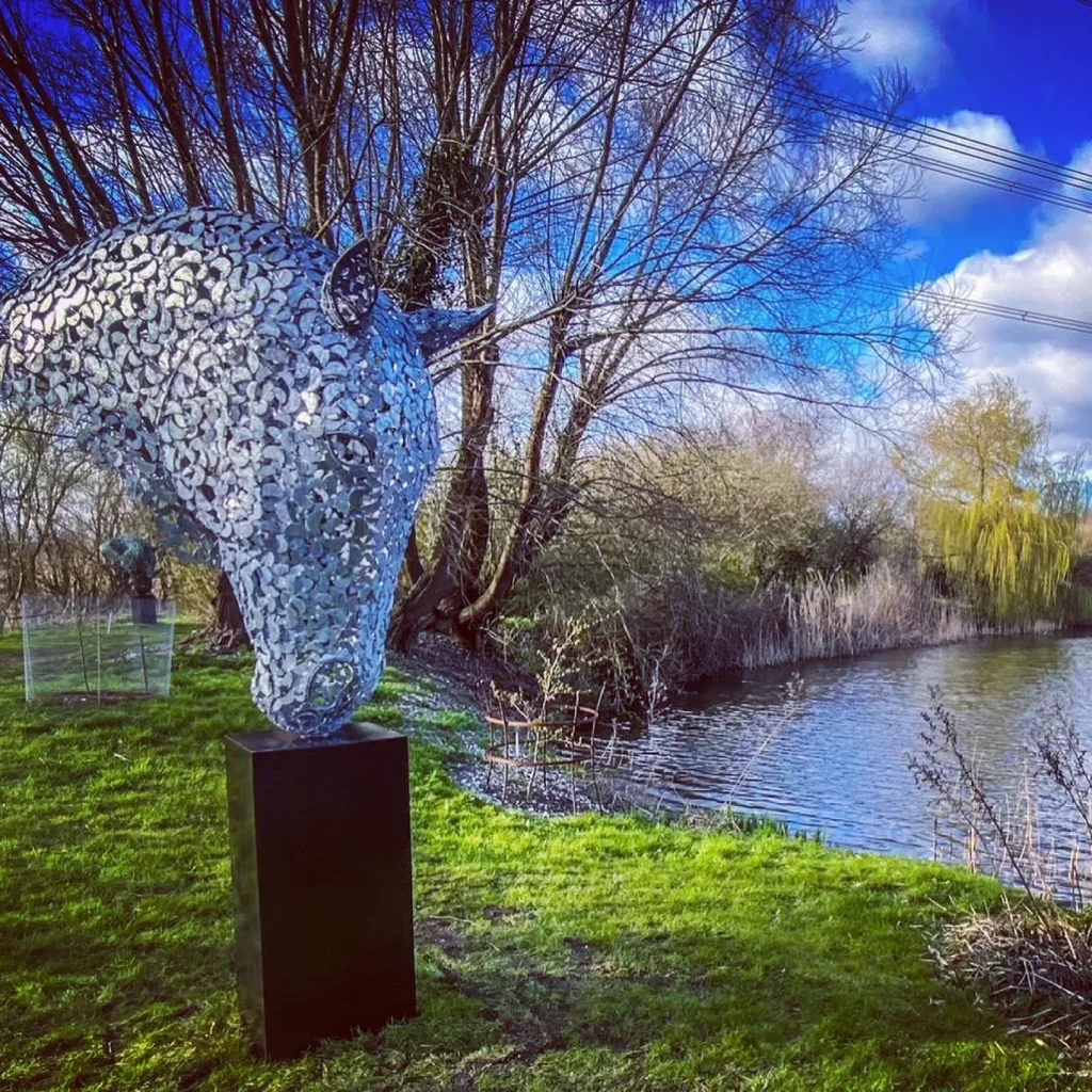 silver horse head sculpture next to a lake