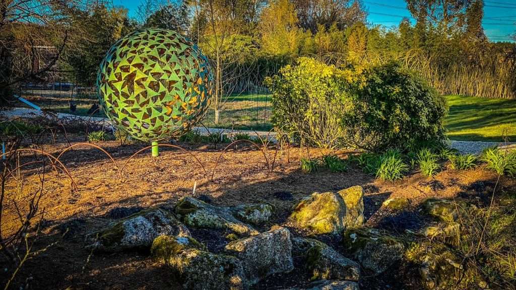 green sphere sculpture in wooded area