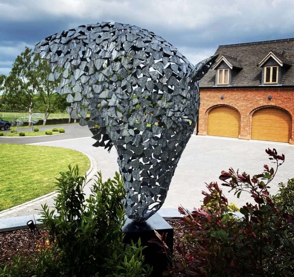 silver horse head sculpture surrounded by plants
