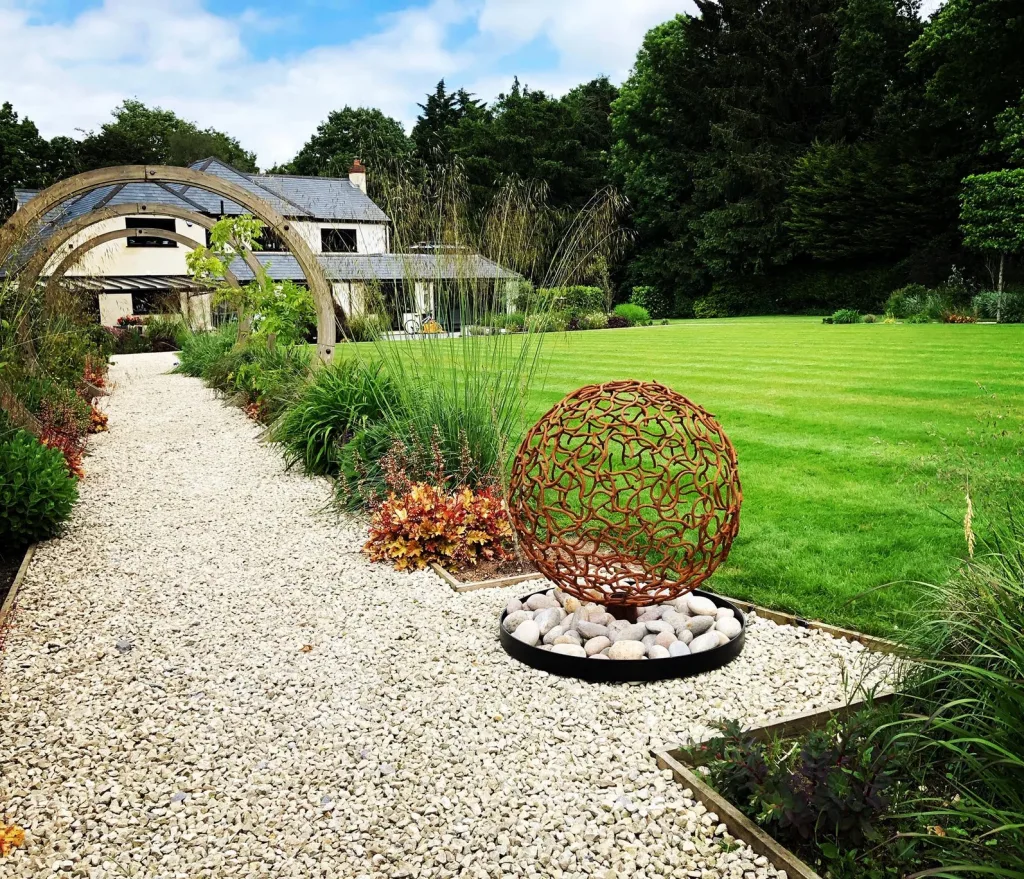 large domestic garden with small brass sphere sculpture