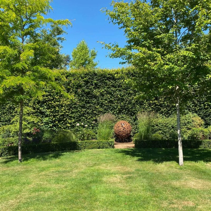 Beech Leaf Sphere Sculpture Surrounded By Shrubbery