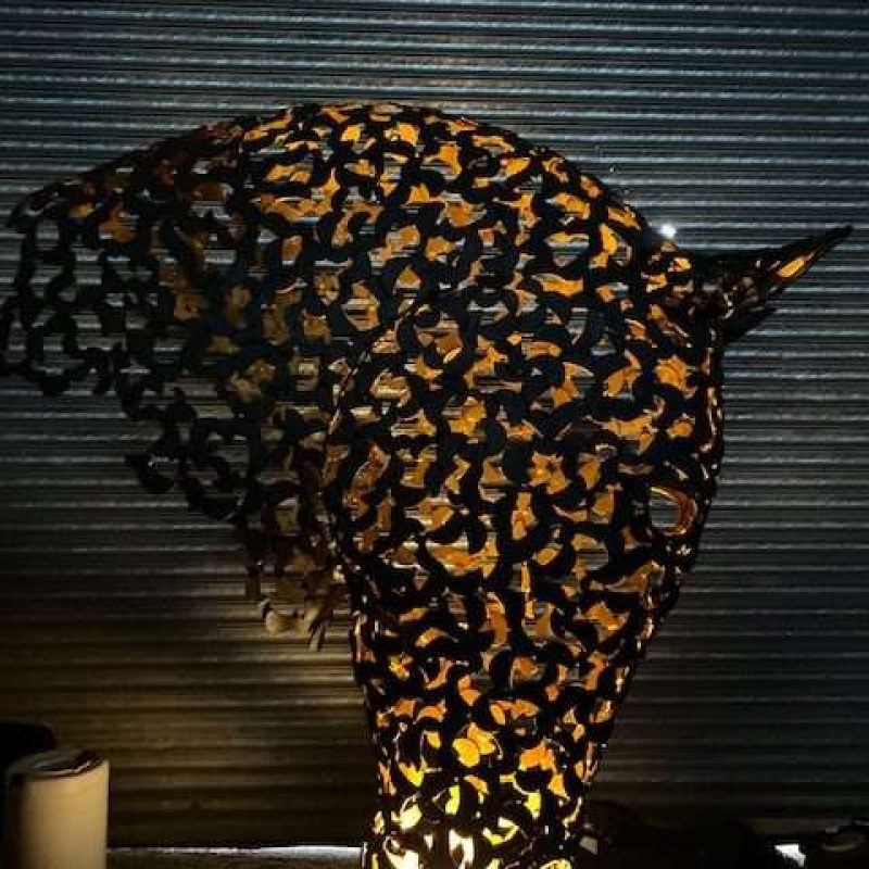 black and gold horse head sculpture lit up looking right