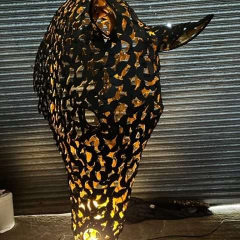 black and gold horse head sculpture lit up looking straight