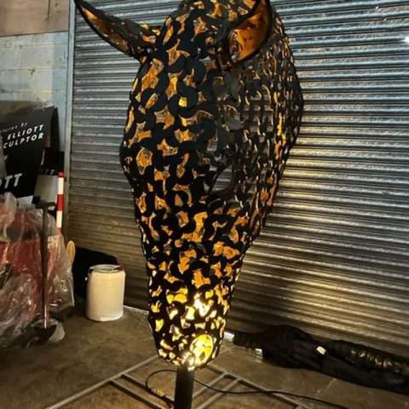 black and gold horse head sculpture lit up looking straight