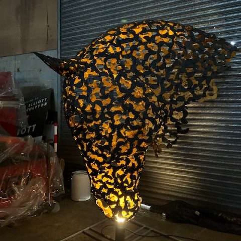 black and gold horse head sculpture lit up looking left