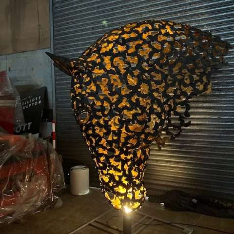 black and gold horse head sculpture lit up looking left