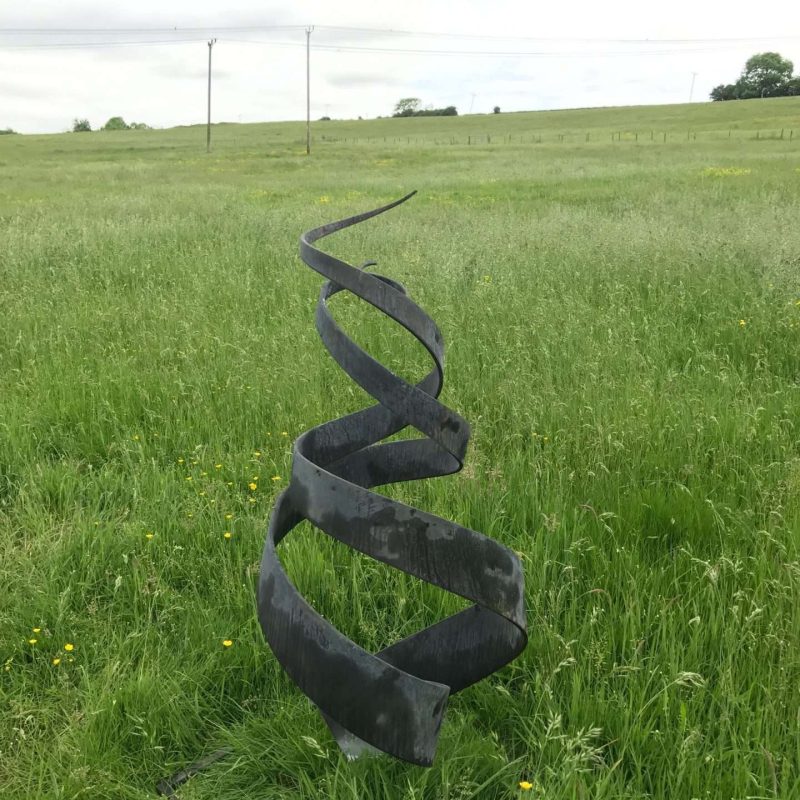Black Spiral Abstract Sculpture In Field