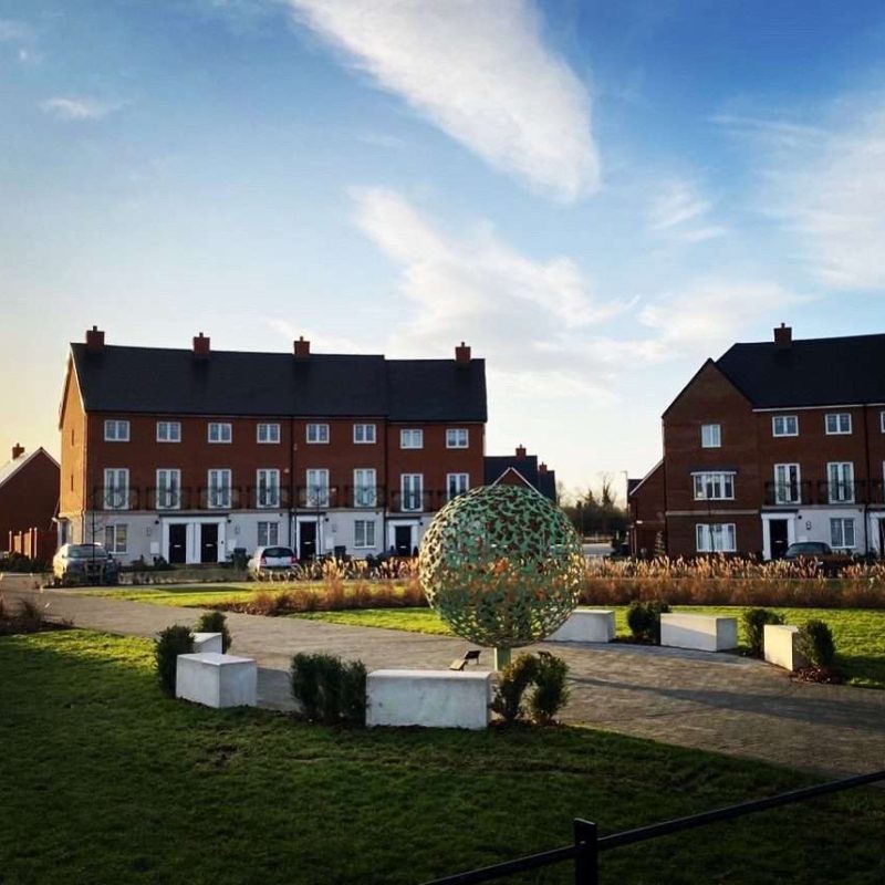 Swift Sphere Sculpture in front of houses
