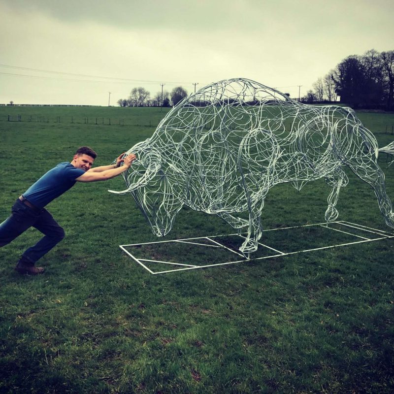 Man Holding On To Bull Sculpture