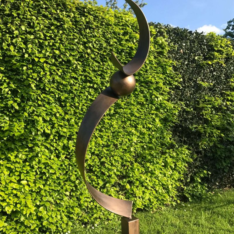 Spiral Structure Sculpture In Front Of A Hedge