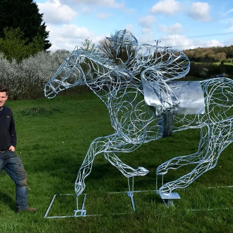 Man Standing Next To Horse and Jokey Sculpture